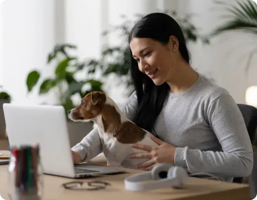 Woman working at a laptop with her dog on her lap